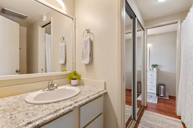 a bathroom with a granite countertop sink a mirror and a shower