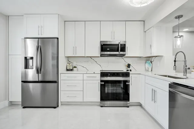 a kitchen with stainless steel appliances white cabinets and a stove top oven