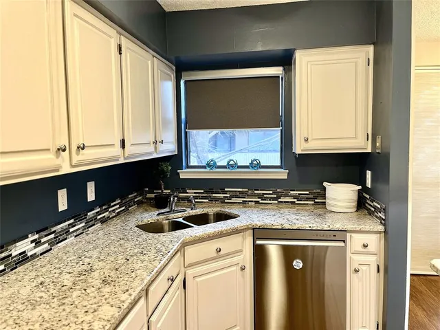 a kitchen with granite countertop a sink a stove and cabinets