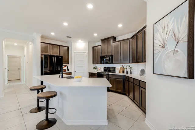 a kitchen with stainless steel appliances granite countertop a refrigerator a sink a stove a dining table and chairs