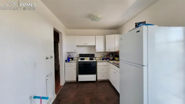 a kitchen with a refrigerator a stove top oven and cabinets
