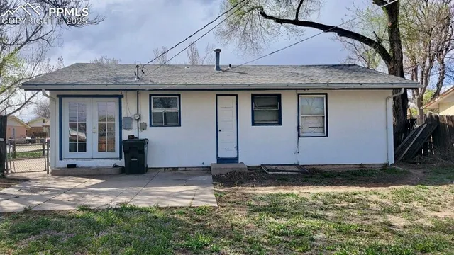 a view of a house with a small yard and large tree
