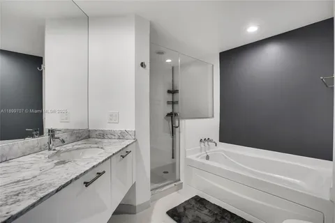 a bathroom with a tub a sink and a large mirror