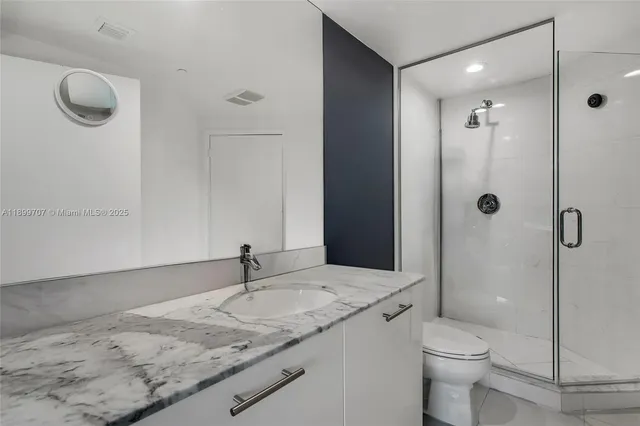 a bathroom with a granite countertop sink a toilet and shower