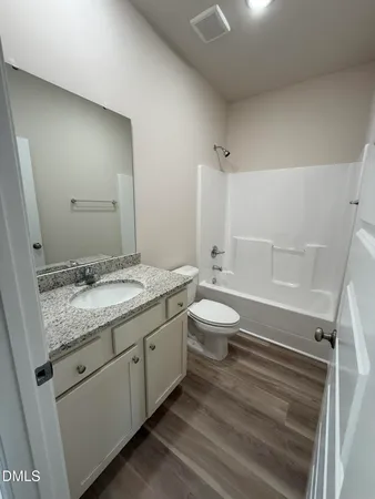 a bathroom with a granite countertop sink mirror vanity and toilet