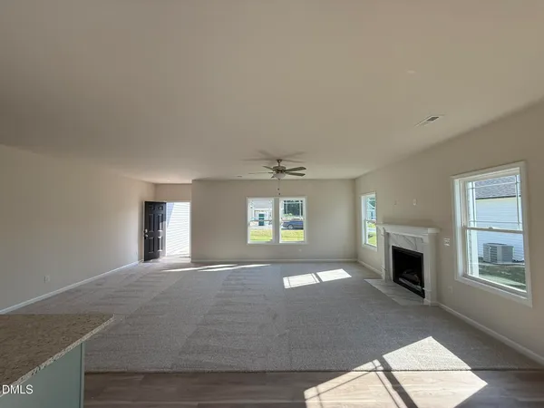 an empty room with windows and fireplace