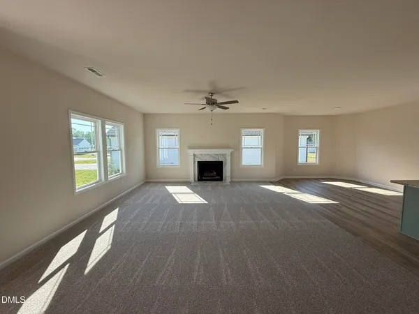an empty room with windows and fireplace