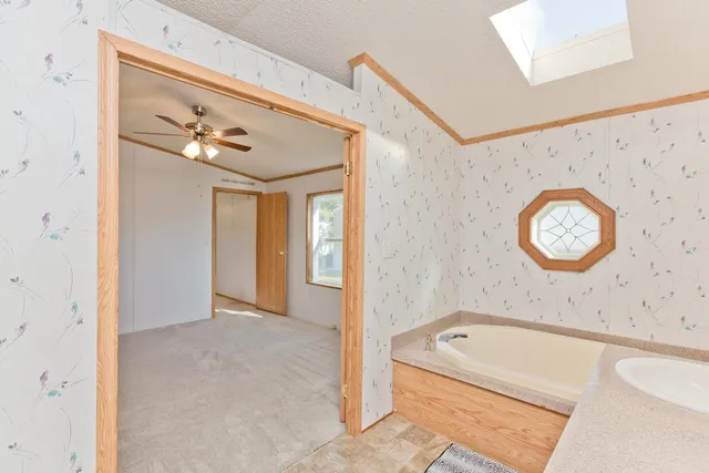 an empty room with chandelier fan and windows