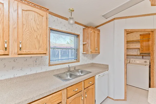 a kitchen with granite countertop a sink cabinets stainless steel appliances and a window