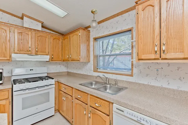 a kitchen with granite countertop a sink stove top oven and cabinets