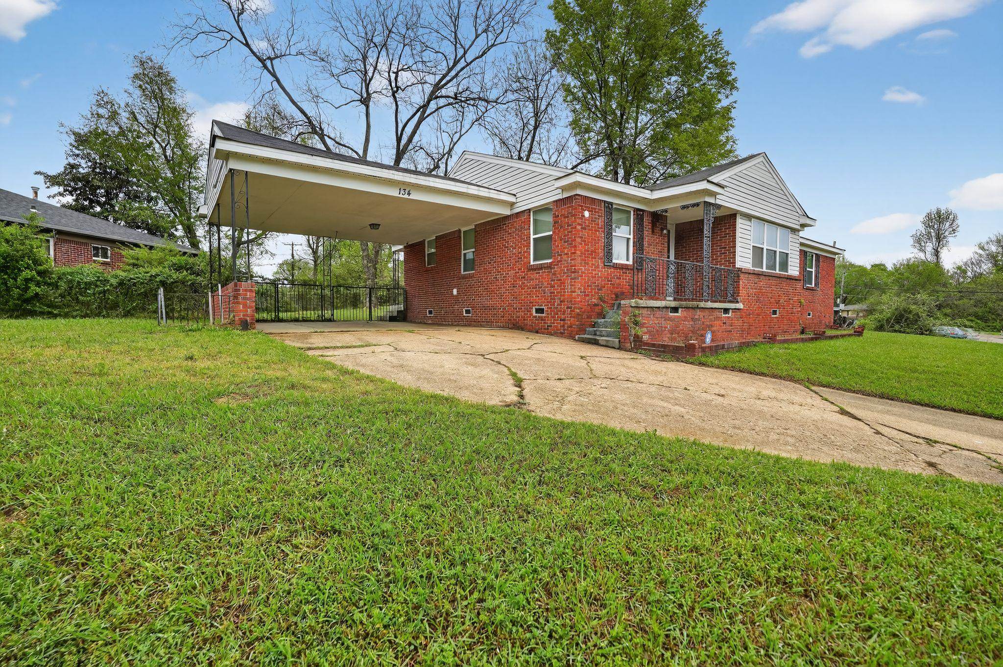 View of front of home featuring crawl space, brick siding, concrete driveway, and an attached carport