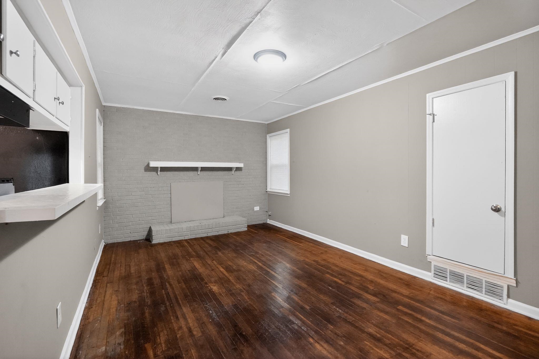 134 West Holmes Road Memphis, TN 38109 - Photo 15 of 30 Unfurnished living room featuring brick wall, dark wood-type flooring, and crown molding