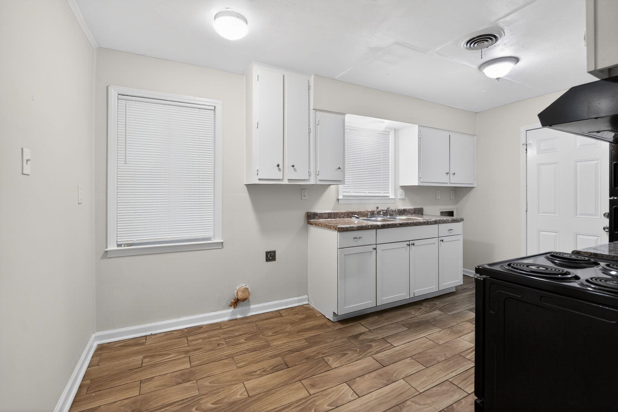 134 West Holmes Road Memphis, TN 38109 - Photo 19 of 30 Kitchen with white cabinets, wood tiled floors, black electric range, and ventilation hood
