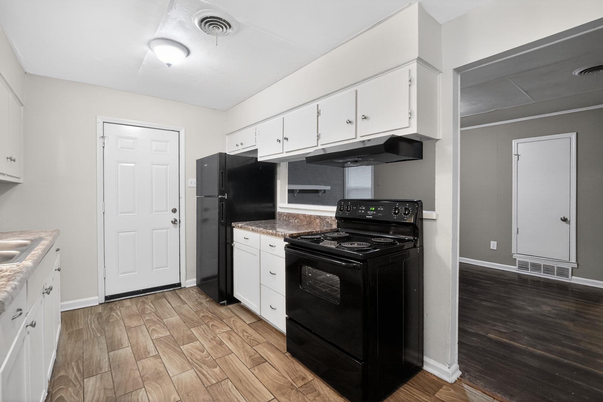 134 West Holmes Road Memphis, TN 38109 - Photo 20 of 30 Kitchen with black appliances, white cabinets, light wood finished floors, and light countertops