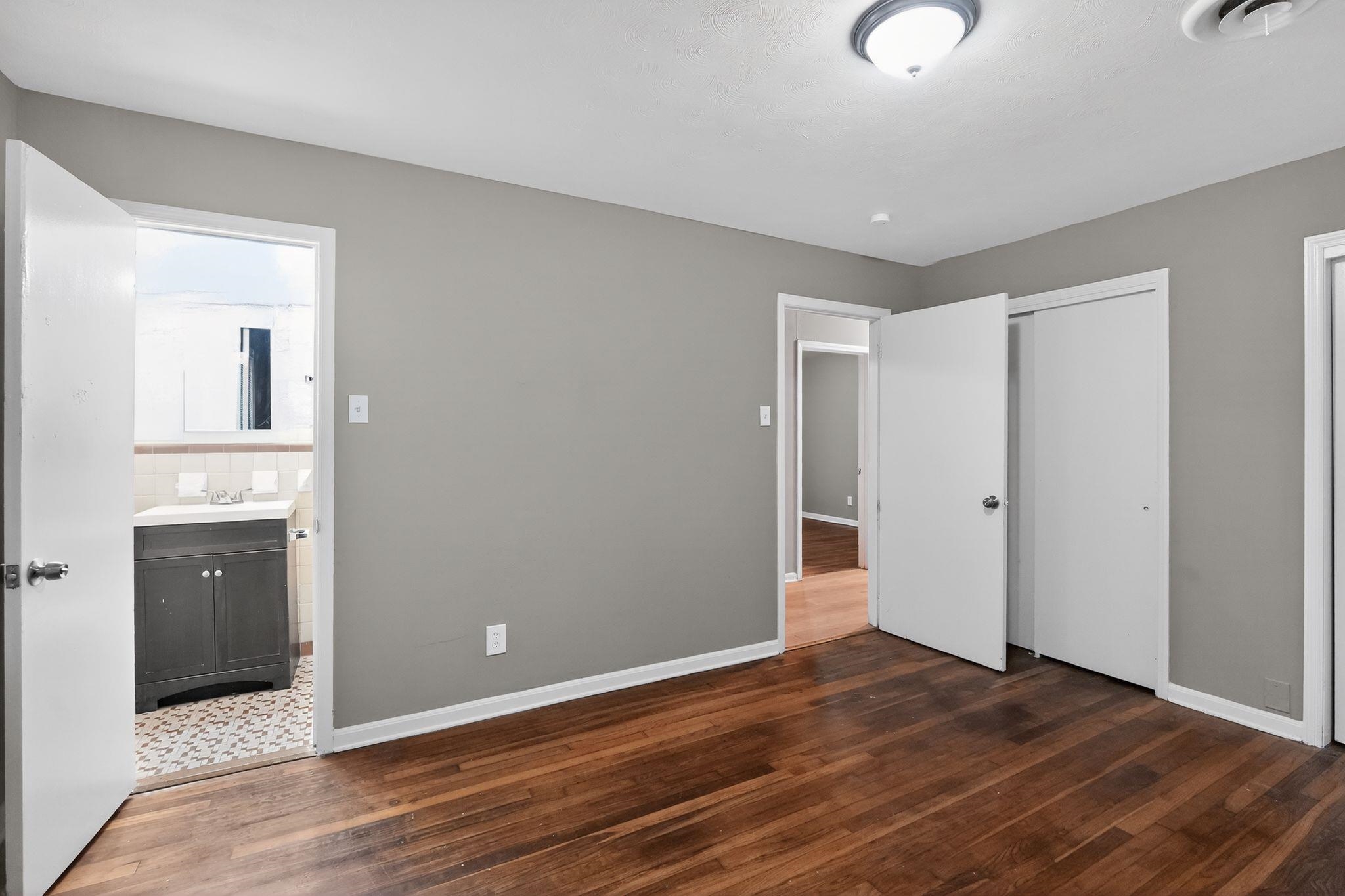 134 West Holmes Road Memphis, TN 38109 - Photo 22 of 30 Unfurnished bedroom with dark wood-style floors, two closets, and ensuite bath