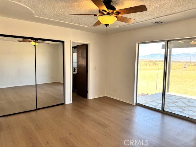 36749 Esaw Road Lucerne Valley, CA 92356 - Photo 11 of 22 an empty room with wooden floor fan and windows