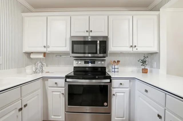 a kitchen with white cabinets and appliances