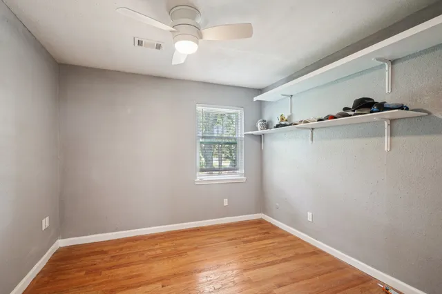 a view of an empty room with window and wooden floor