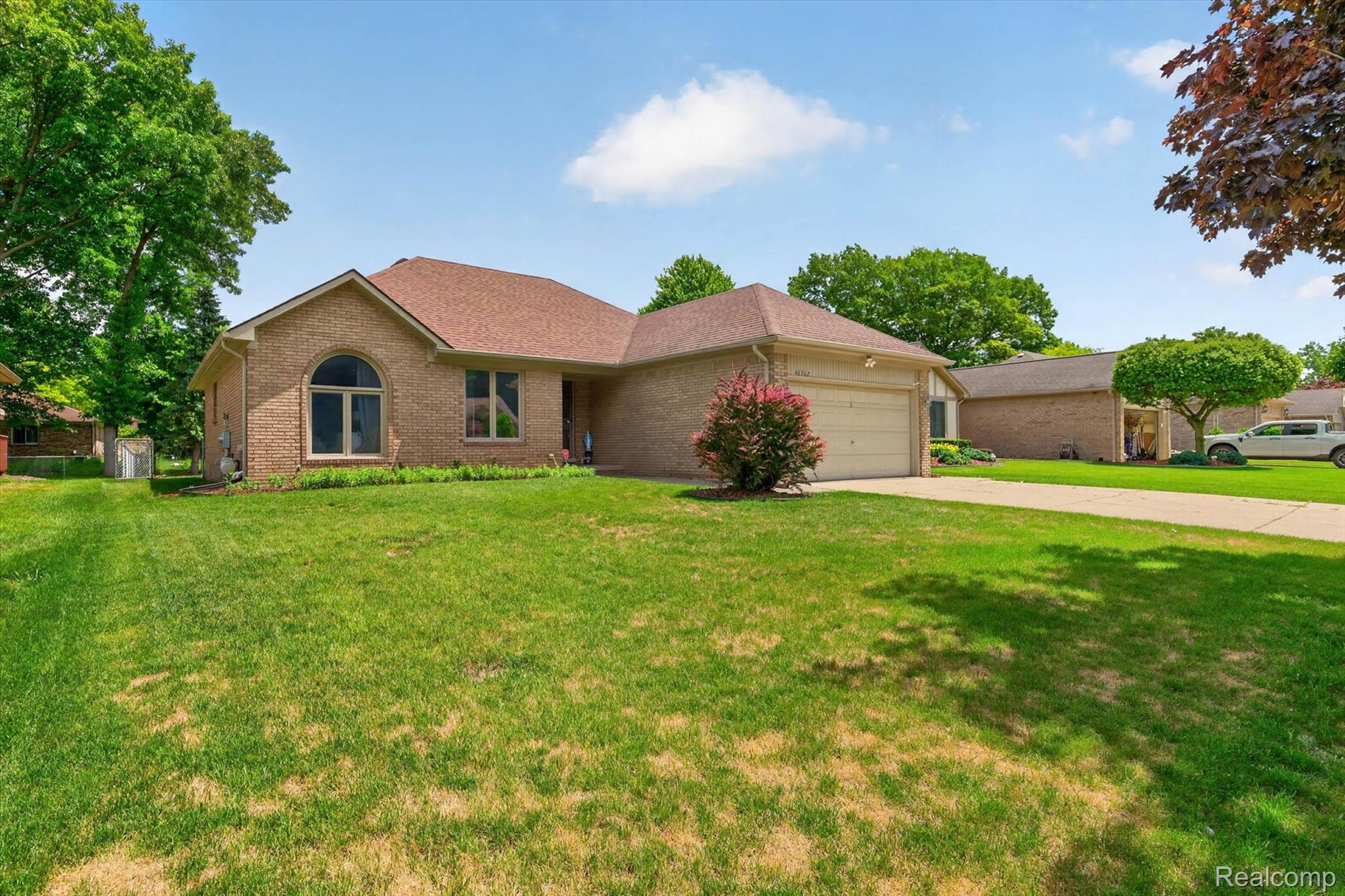 46362 Springhill Drive Utica, MI 48317 - Photo 2 of 59 Brick exterior residence featuring an attached garage, arched window, and a gabled roofline