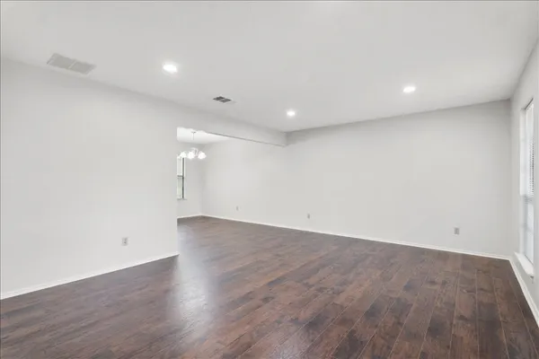 an empty room with wooden floor and natural light