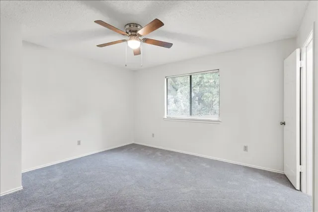 an empty room with windows and fan