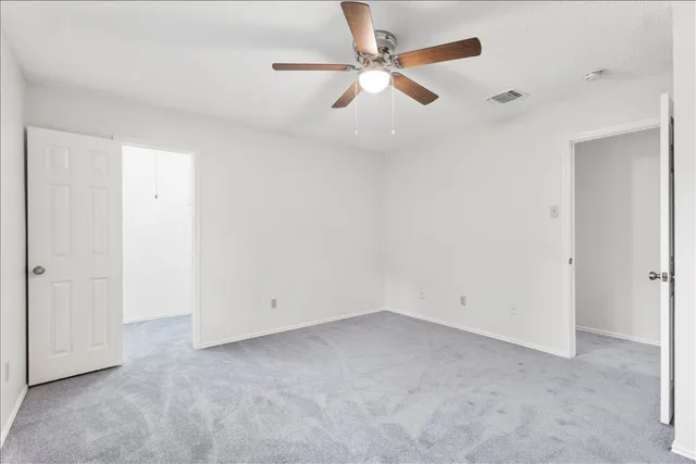 an empty room with a ceiling fan and wooden floor