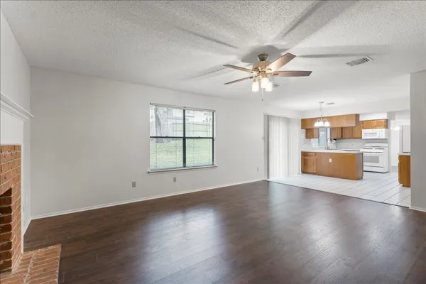 a view of a livingroom with a kitchen stove wooden floor and a ceiling fan