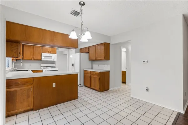 a large kitchen with stainless steel appliances a large counter top a sink and a chandelier