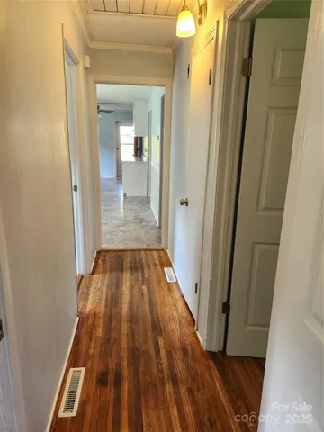 a view of a hallway with wooden floor and a bathroom