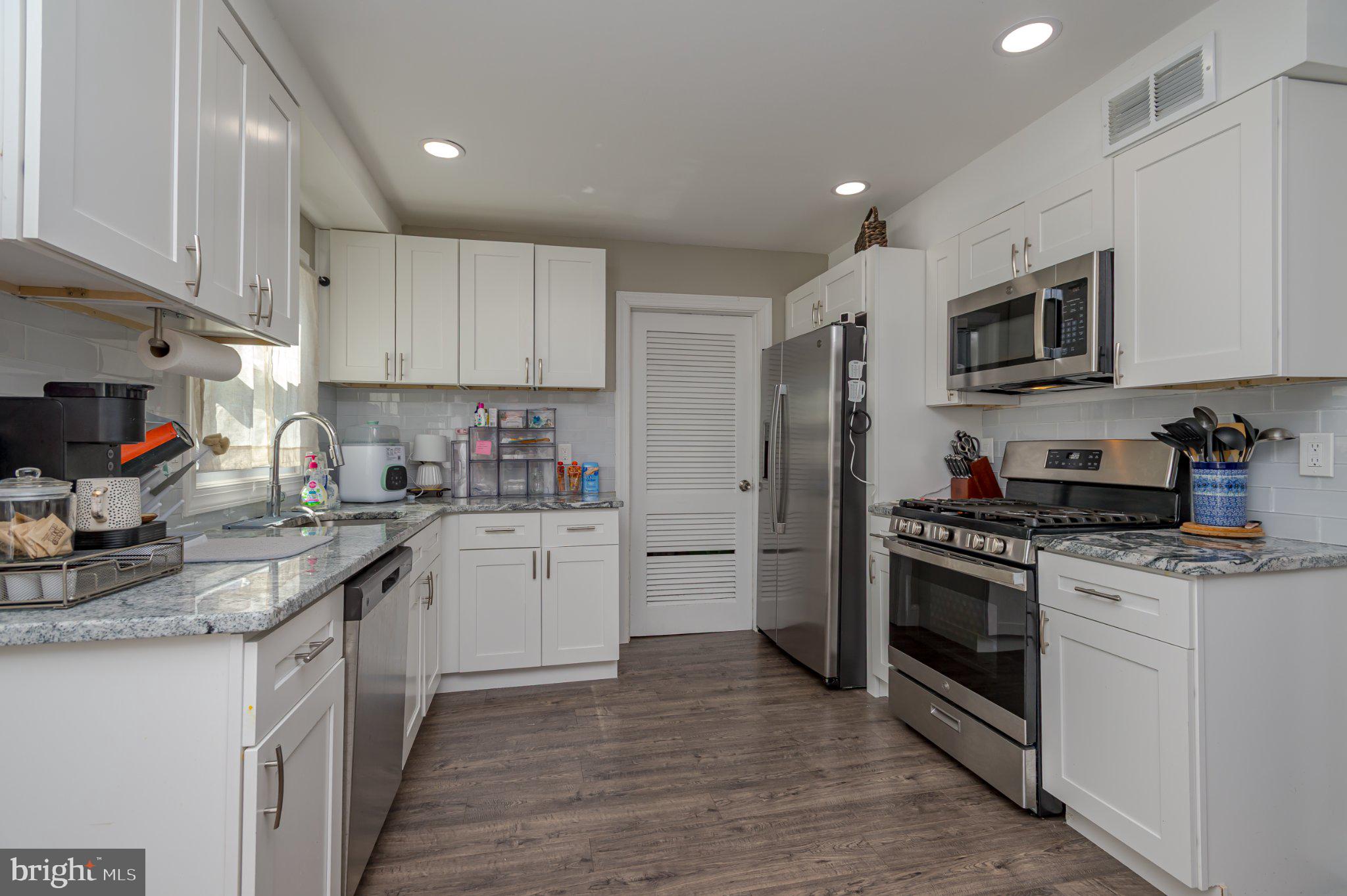 60 Midvale Lane Willingboro, NJ 08046 - Photo 9 of 24 a kitchen with stainless steel appliances granite countertop a stove top oven a sink dishwasher a refrigerator and white cabinets with wooden floor