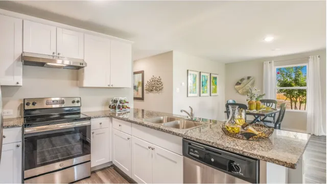 a kitchen with granite countertop a sink a stove and refrigerator
