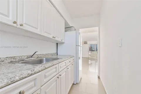 a kitchen with granite countertop a sink and a refrigerator
