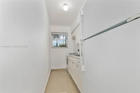 a hallway with white cabinets and white appliances