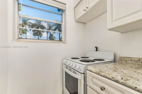 a kitchen with granite countertop white cabinets and a stove