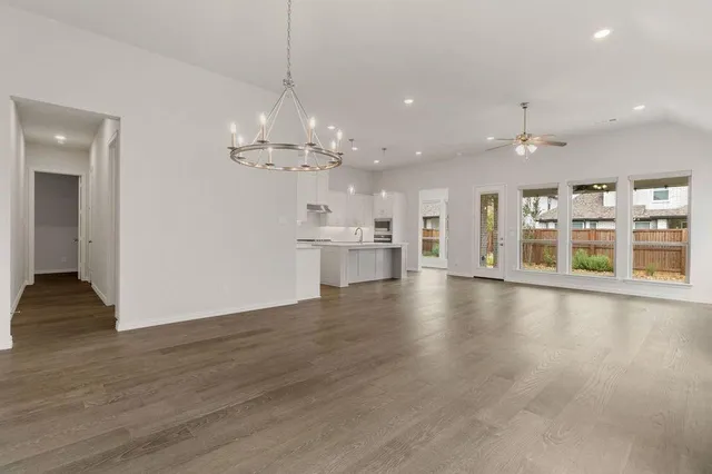 a view of an empty room and kitchen with ceiling fan kitchen view