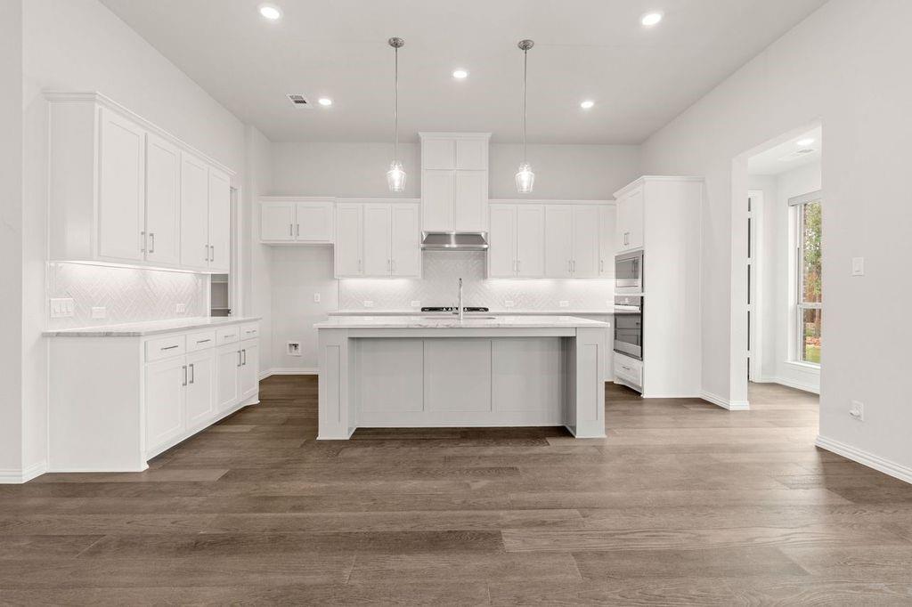 1636 Hydrangea Lane Prosper, TX 75078 - Photo 15 of 31 a view of kitchen with kitchen island sink stove and white cabinets