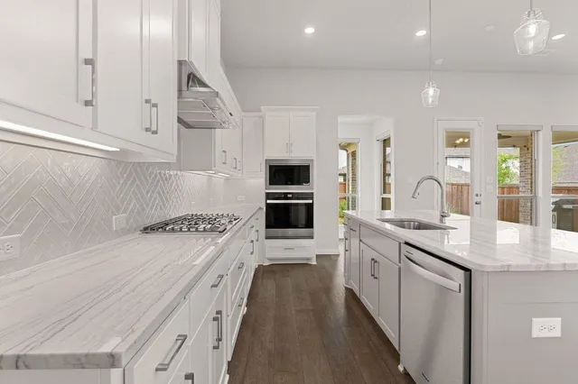 a kitchen with white cabinets appliances and sink