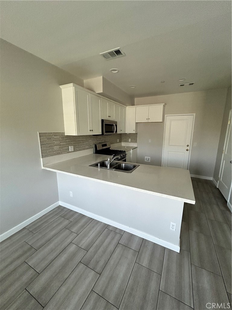 13665 Arrow Route, Unit 9 Fontana, CA 92335 - Photo 11 of 43 a kitchen with stainless steel appliances a sink a stove a microwave a sink a refrigerator and cabinets