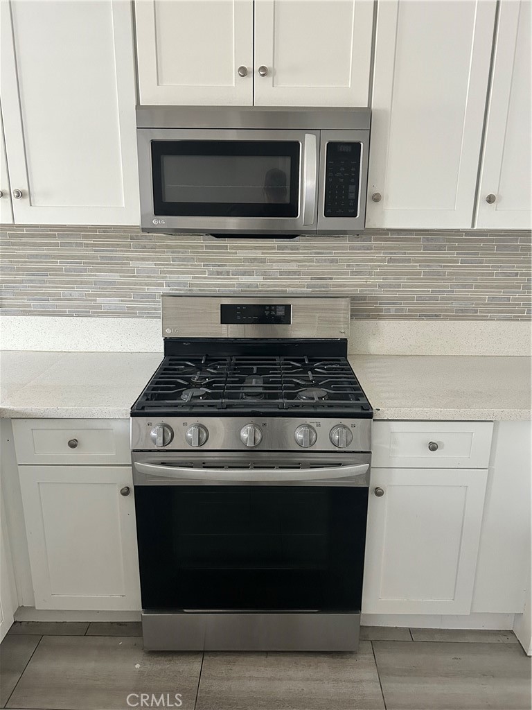 13665 Arrow Route, Unit 9 Fontana, CA 92335 - Photo 13 of 43 a stove top oven sitting inside of a kitchen and white cabinets