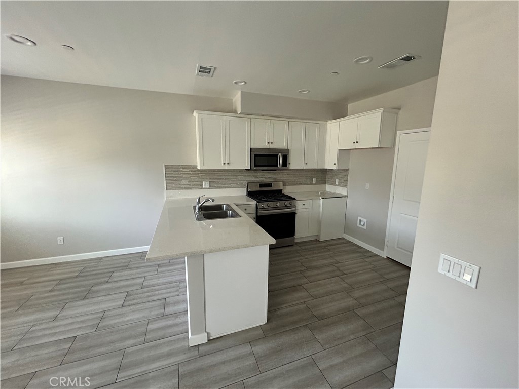 13665 Arrow Route, Unit 9 Fontana, CA 92335 - Photo 5 of 43 a kitchen with a sink a stove top oven and white stainless steel appliances