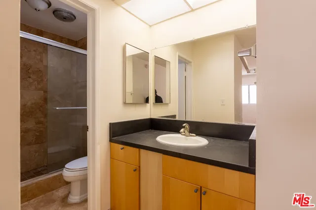 a bathroom with a granite countertop sink toilet and shower