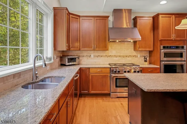 a kitchen with stainless steel appliances granite countertop a sink a stove and a wooden cabinets