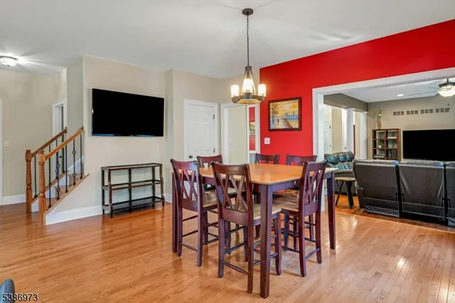 a view of a dining room and livingroom with furniture wooden floor a flat screen tv a painting and a chandelier