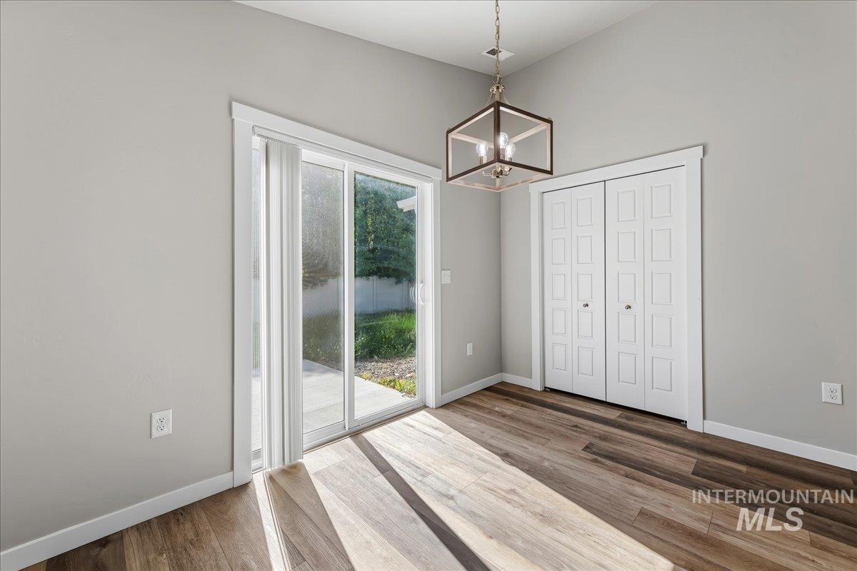 3091 S Green Boise, ID 83709 - Photo 8 of 27 Dining area with wood-finish flooring, a contemporary geometric chandelier, and sliding glass doors to the exterior