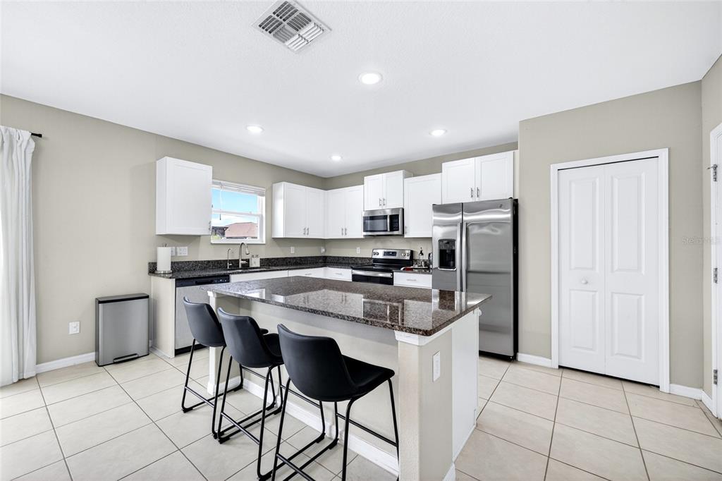 31724 Sun Kettle Loop Wesley Chapel, FL 33545 - Photo 6 of 49 a kitchen with stainless steel appliances granite countertop a refrigerator a sink a stove a dining table and chairs