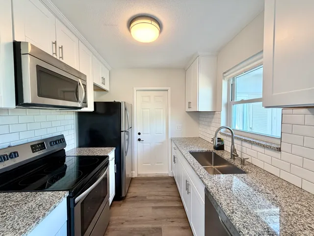a kitchen with stainless steel appliances granite countertop a sink stove and microwave