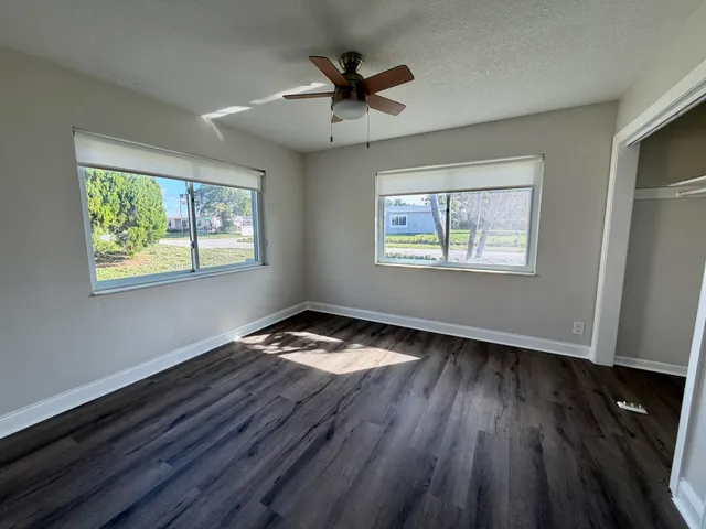 a view of empty room with wooden floor and fan