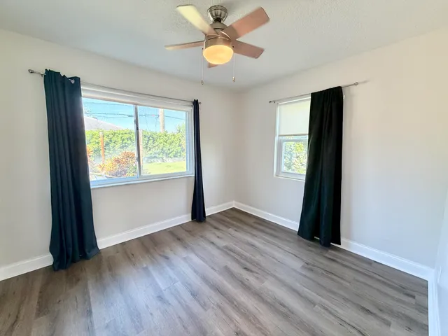 a view of an empty room with window and wooden floor