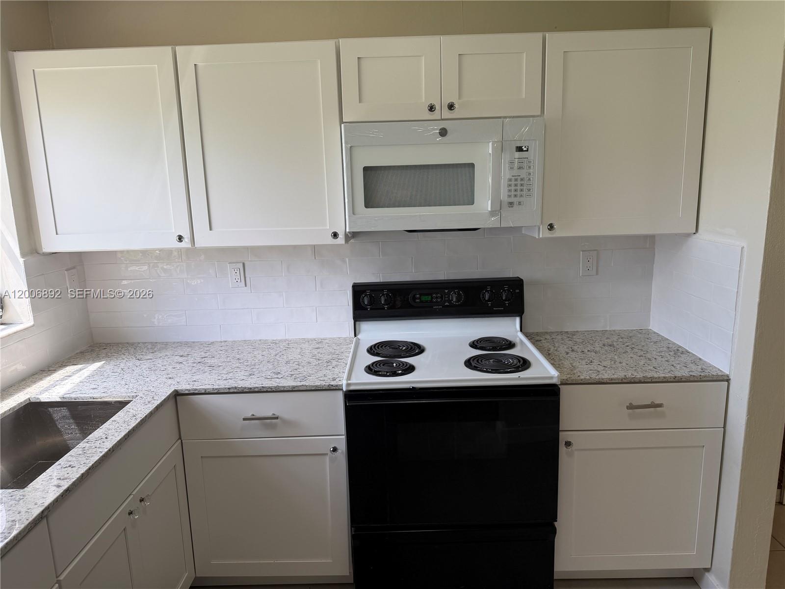 10375 Southwest 152nd Terrace Miami, FL 33157 - Photo 13 of 59 a kitchen with granite countertop white cabinets and white appliances