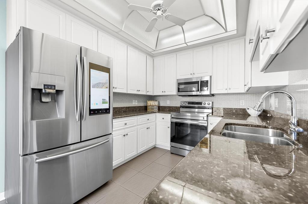 5 Barbados Road, Unit 31 Englewood, FL 34223 - Photo 7 of 40 a kitchen with stainless steel appliances granite countertop a refrigerator a stove a sink and a microwave